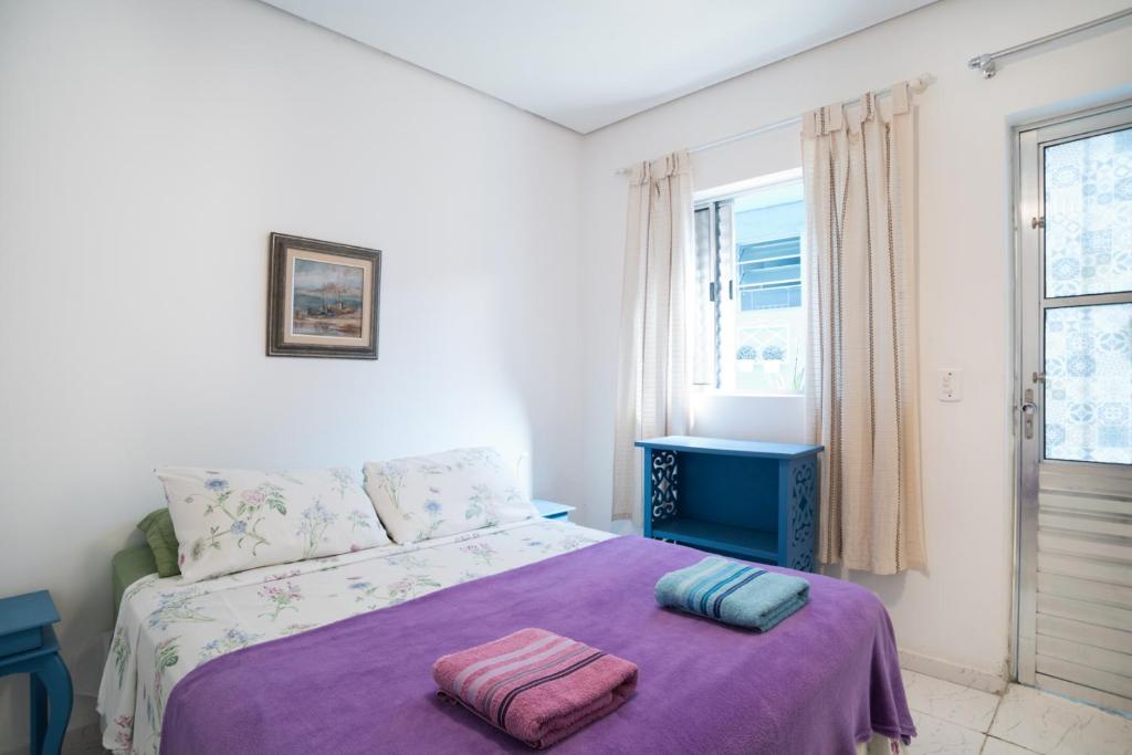 una camera da letto con un letto con una coperta viola e una finestra di Aconchego Azul Suítes Vila Mariana a San Paolo