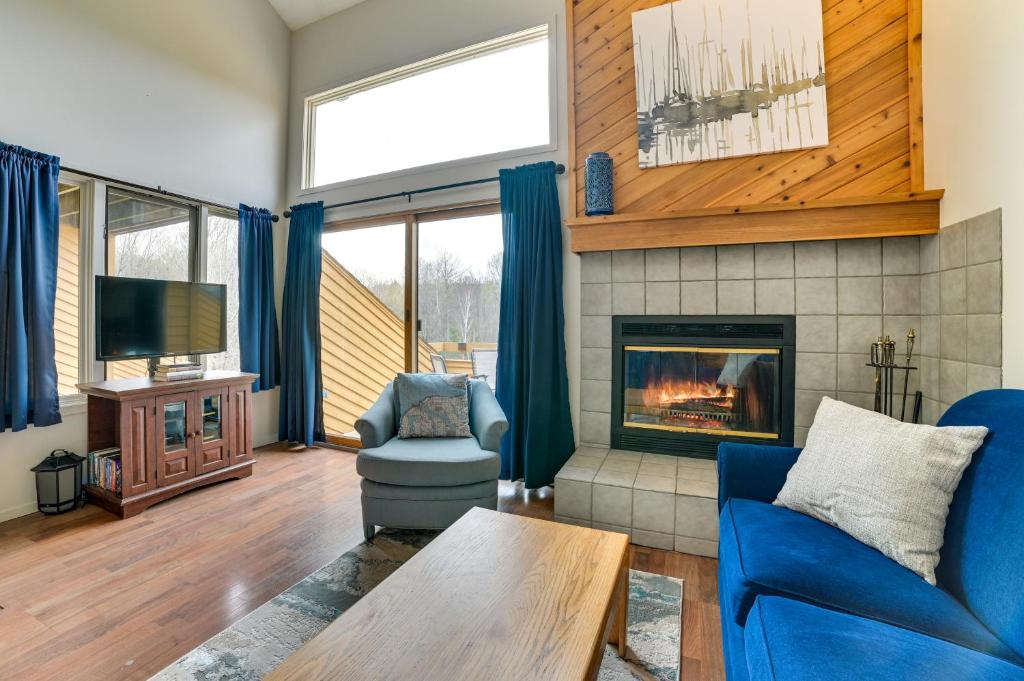 ein Wohnzimmer mit einem blauen Sofa und einem Kamin in der Unterkunft Trout Creek Resort Condo - 1 Mi to Nubs Nob! in Harbor Springs