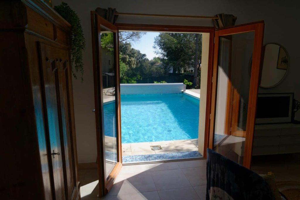 - une vue sur la piscine par une porte en verre dans l'établissement Les Hauts de Saint Siffret, à Saint-Siffret