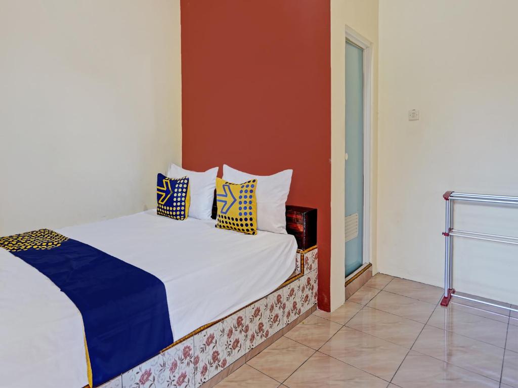 1 dormitorio con 1 cama con almohadas azules y amarillas en SPOT ON 92527 Penginapan Kangean Syariah, en Sumenep