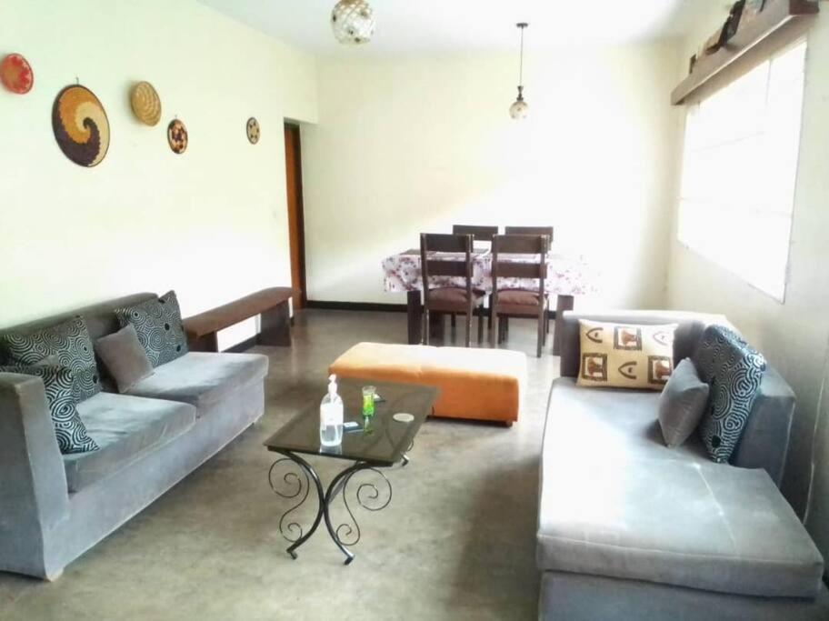 a living room with two couches and a table at Maison de 3 chambres dans un lieu apaisé au centre de Kigali in Kigali