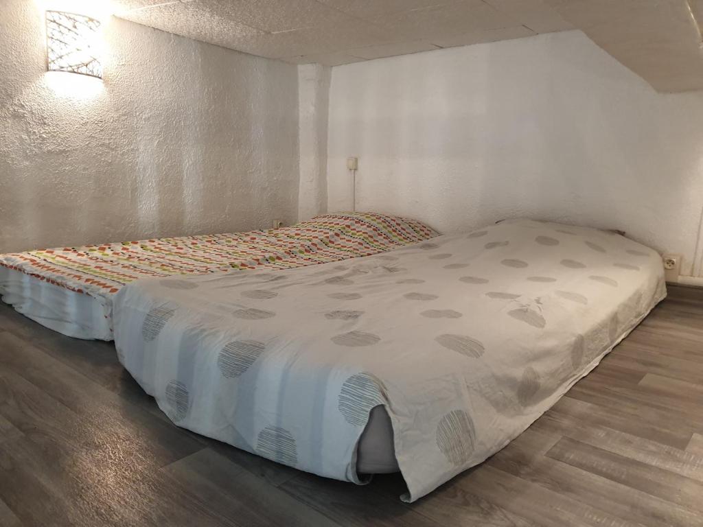 łóżko w niewielkim pokoju z prześcieradłem w obiekcie Au pied du Baou w mieście Saint-Chamas