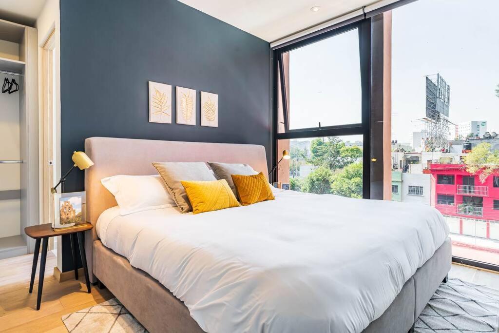 a large bed in a room with a large window at Cómodo y nuevo depto. en excelente zona. in Mexico City
