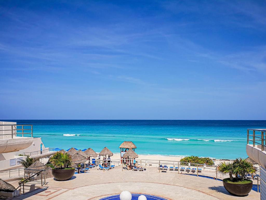 una playa con sombrillas y sillas y el océano en Villa Aurora Beautiful Beachfront Apartment en Cancún