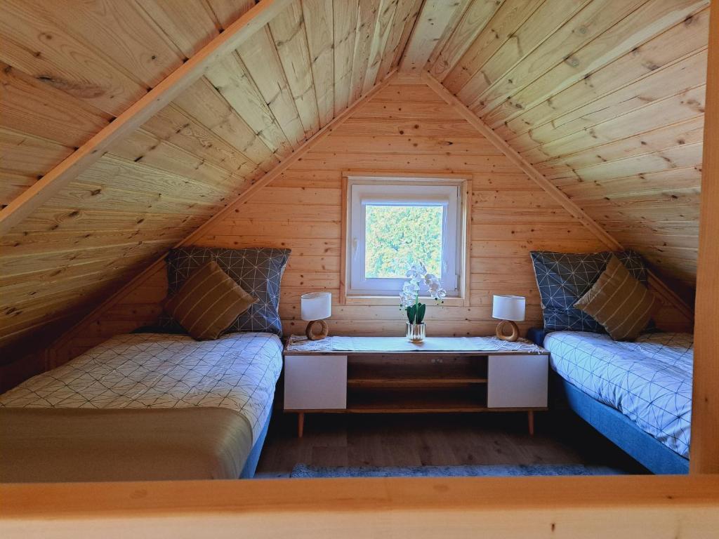 um quarto com duas camas e uma mesa num sótão em Domki Na Wzgórzu - domek nr 1 em Mrągowo
