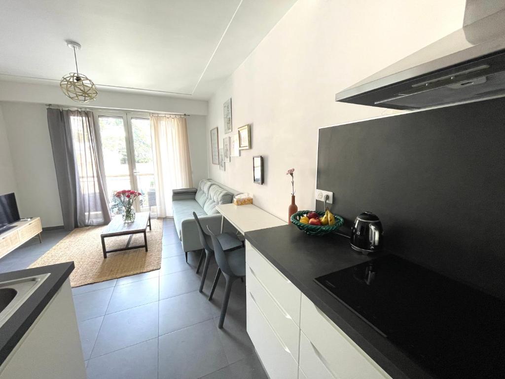 een keuken met een zwart aanrecht en een woonkamer bij Les Constellations in Beaulieu-sur-Mer