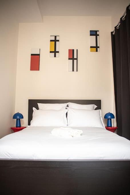 a bedroom with a white bed with pictures on the wall at LE MONDRIAN - Hôtel de ville - Confort - Paisible - Wi-Fi in Saint-Étienne