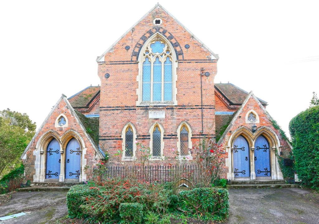 uma velha igreja de tijolos com portas e janelas azuis em The Old Chapel Annexe em Nayland