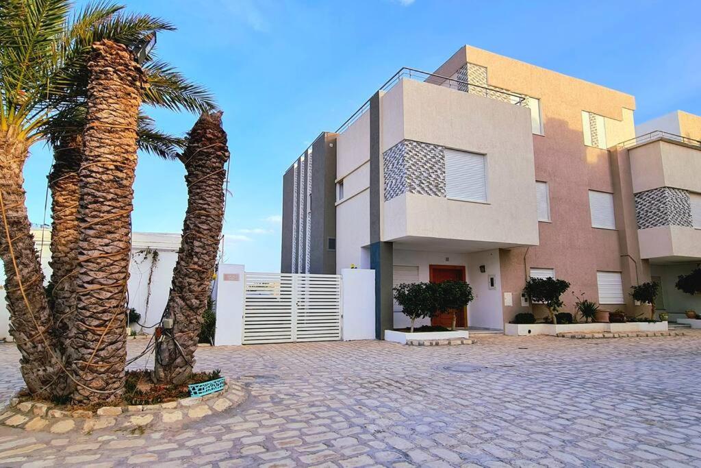 a building with palm trees in front of it at Villa ilian in Monastir