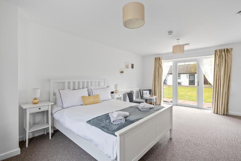 a bedroom with a large white bed and a window at Number 5 - Lytton Tree Lodge, Reydon, Southwold in Reydon
