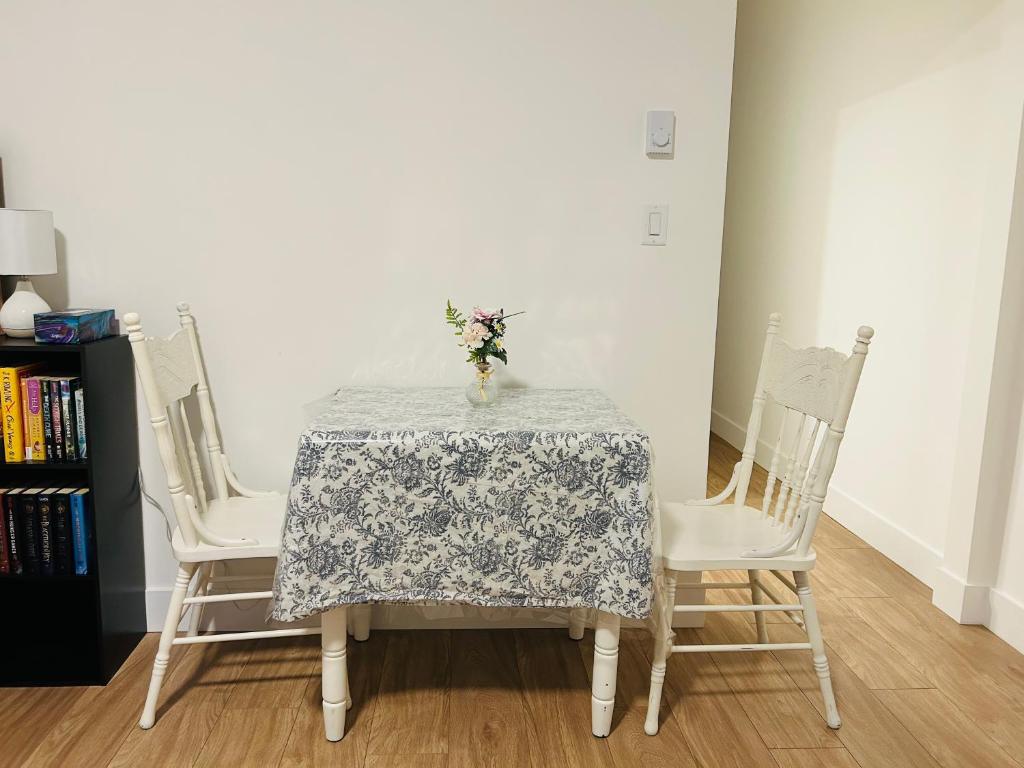 a table with two chairs and a vase with flowers on it at Victoria private studio suite in Victoria