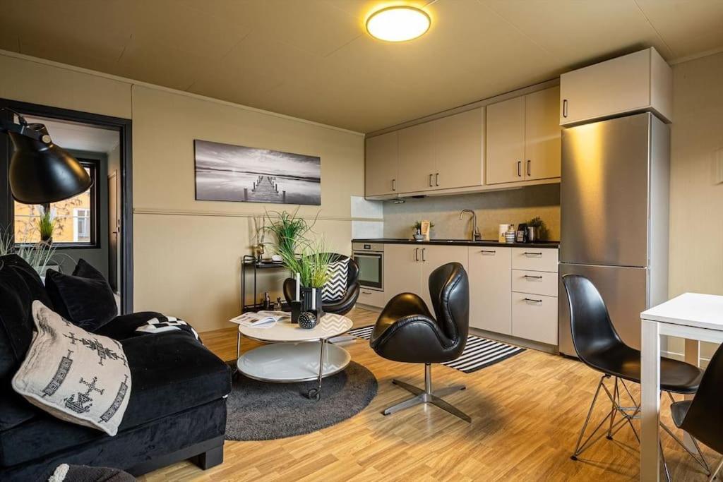 sala de estar con sofá y sillas y cocina en Flott leilighet MIDT i Tønsberg!, en Tønsberg
