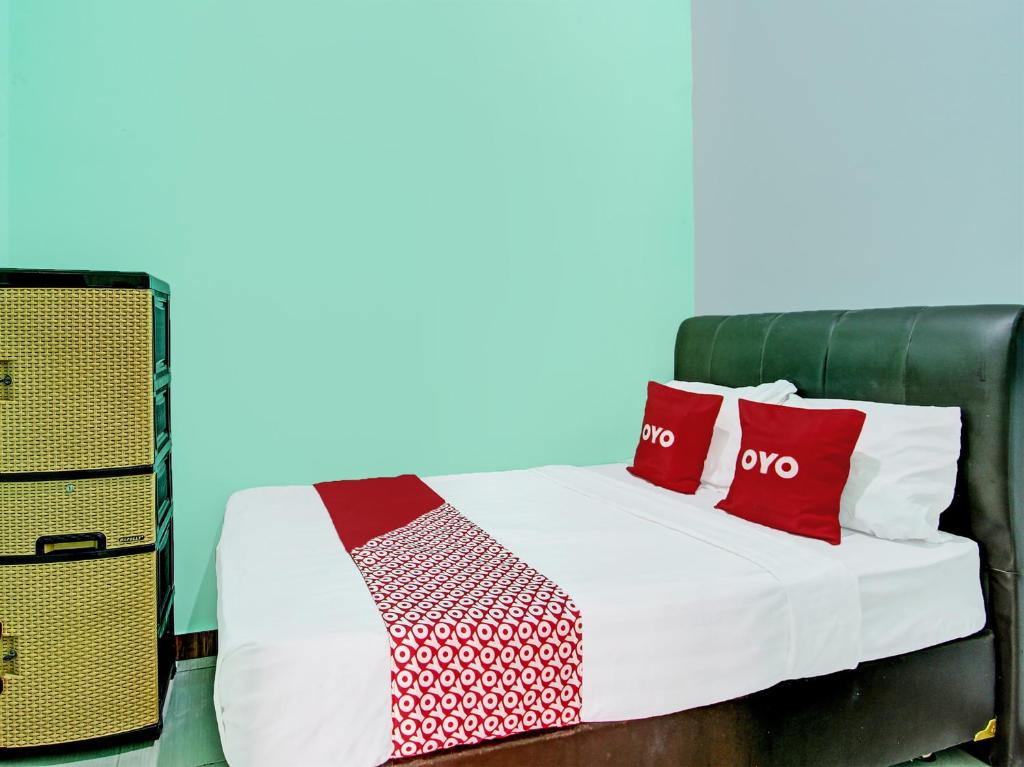 Una cama con almohadas rojas y blancas. en OYO 92521 Guest House Inayah Syariah en Yogyakarta