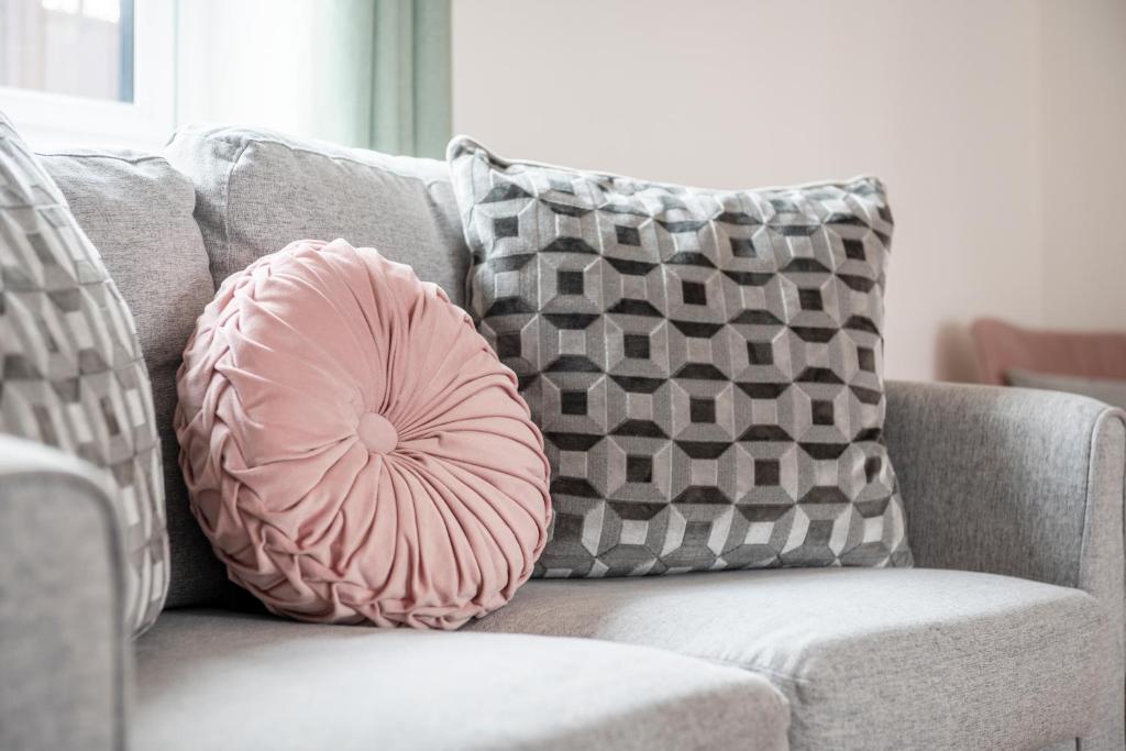 uma almofada rosa sentada num sofá com almofadas em Number 1 Lytton Tree Lodge em Reydon