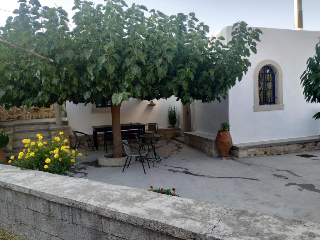 un patio con un árbol, mesas y sillas en xenios Z rustic rural cottage, en Karídhion