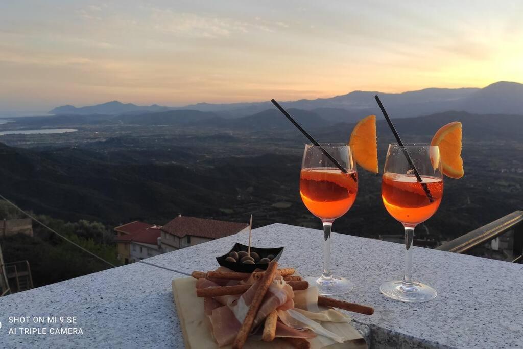dois copos de vinho e um prato de comida numa mesa em Window on the Ogliastra apartment in Baunei em Baunei