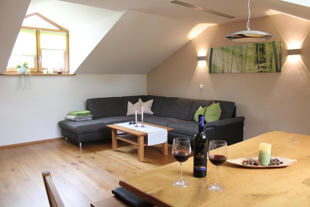 ein Wohnzimmer mit einem Sofa und einem Tisch mit Weingläsern in der Unterkunft Ferienwohnung am Dreiseithof in Hauzenberg