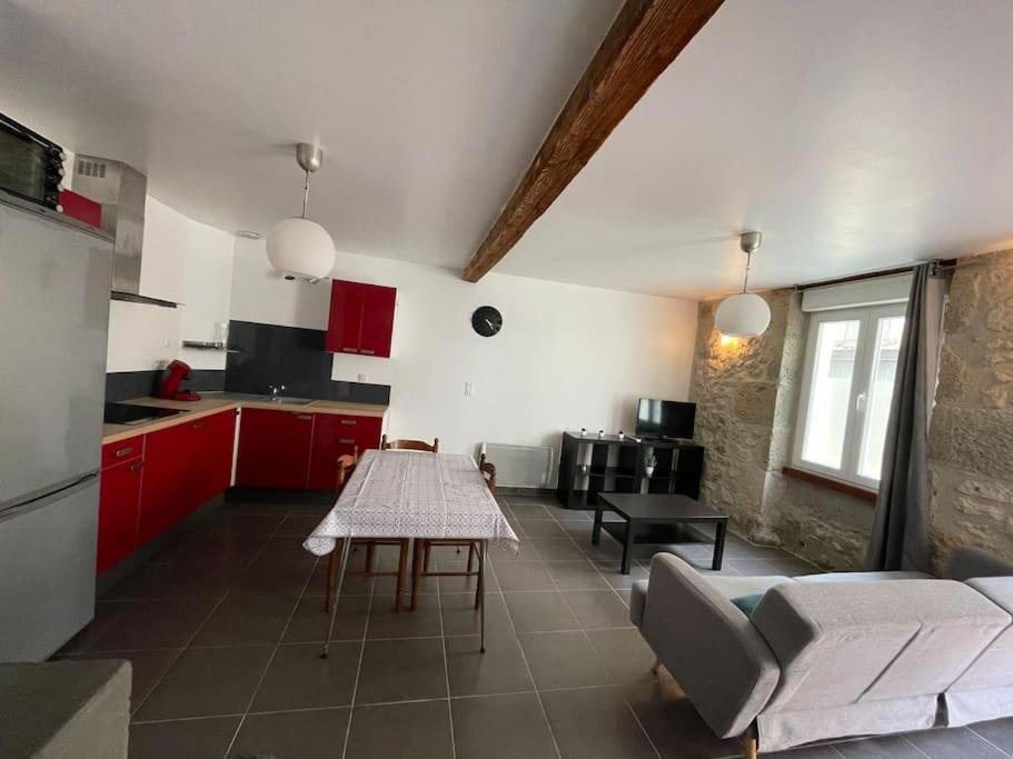 uma cozinha com armários vermelhos e uma mesa em Belle maison de ville rénovée em Lavardac