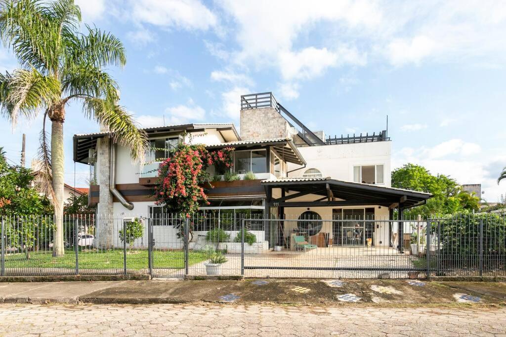 een wit huis met een hek en palmbomen bij Patz Houz Hostel in Florianópolis