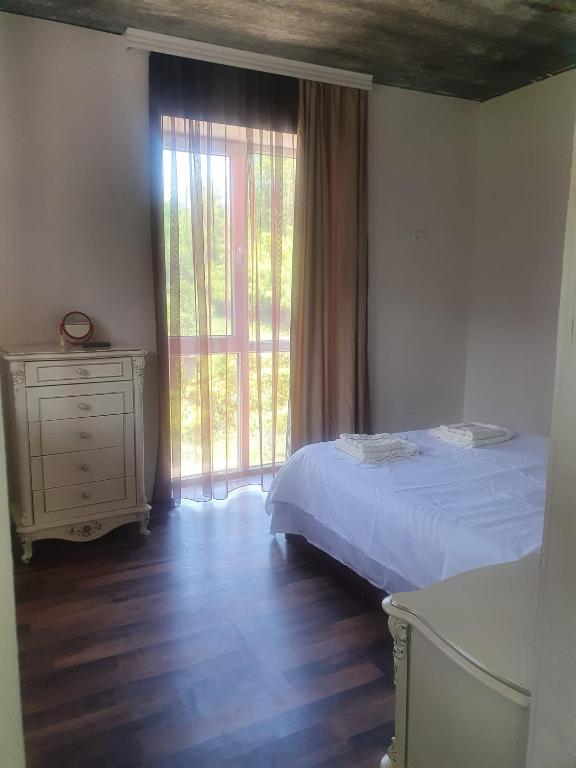 a bedroom with a bed and a dresser and a window at Racha - ABA in Ambrolauri