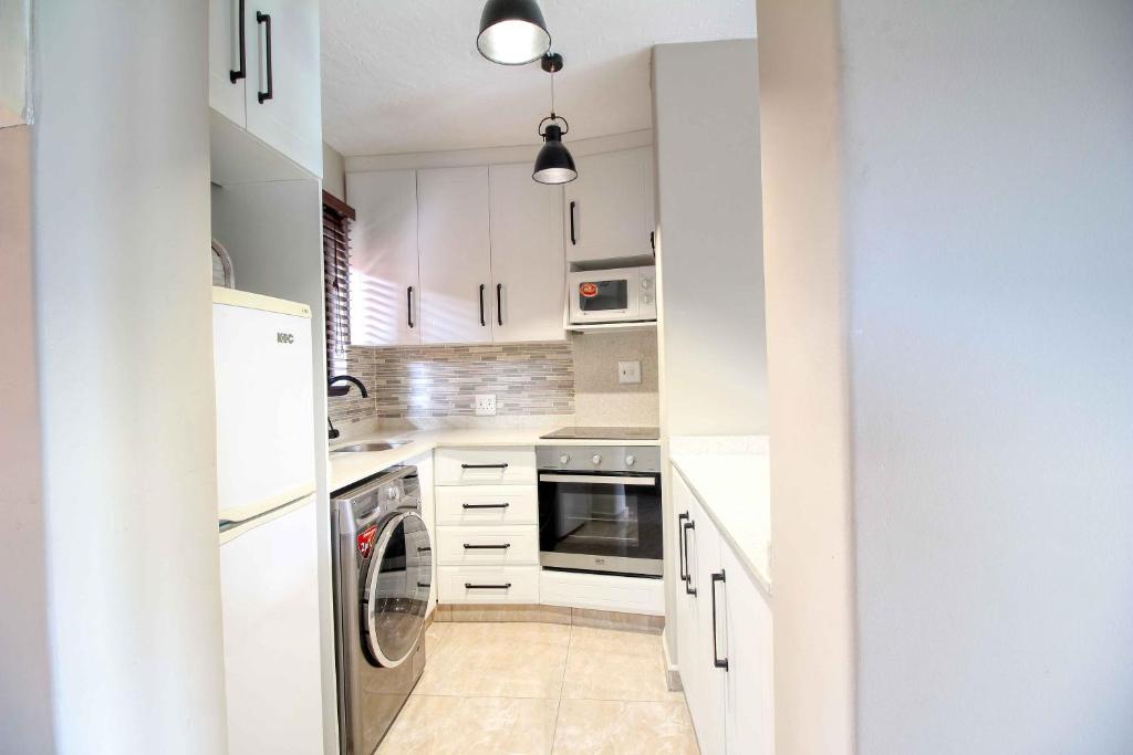 a kitchen with white cabinets and a washer and dryer at San Lameer Villa 2004 by Top Destinations Rentals in Southbroom