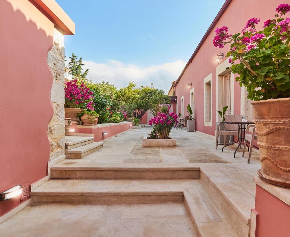 einen Innenhof eines Hauses mit rosa Wänden und Blumen in der Unterkunft Arhontiko Arhanes Suites in Archanes
