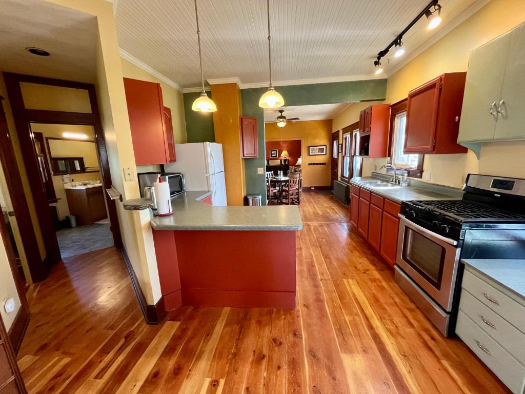 a large kitchen with wooden floors and red cabinets at Elderberry Farmhouse at Zenzen Gardens in Paonia