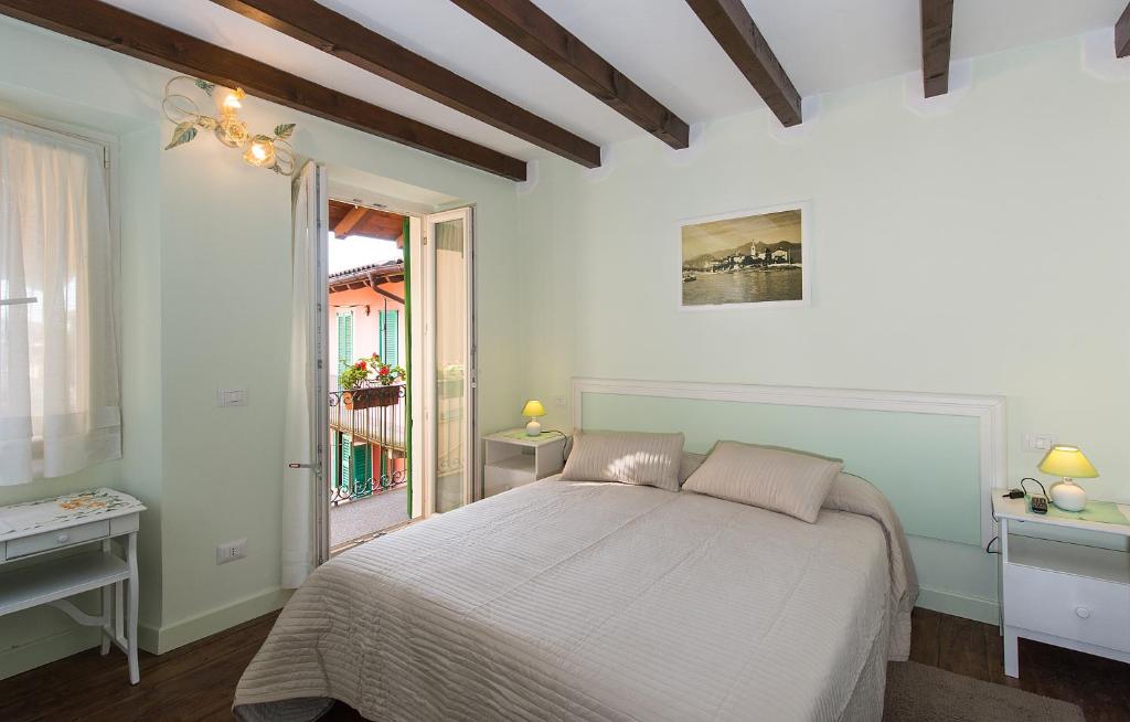 a white bedroom with a bed and a window at B&B Casa del Lago in Baveno