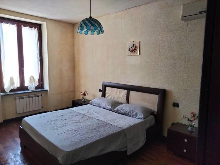 - une chambre avec un grand lit et un lustre bleu dans l'établissement Appartamento in cascina lombarda, à Caselle Lurani