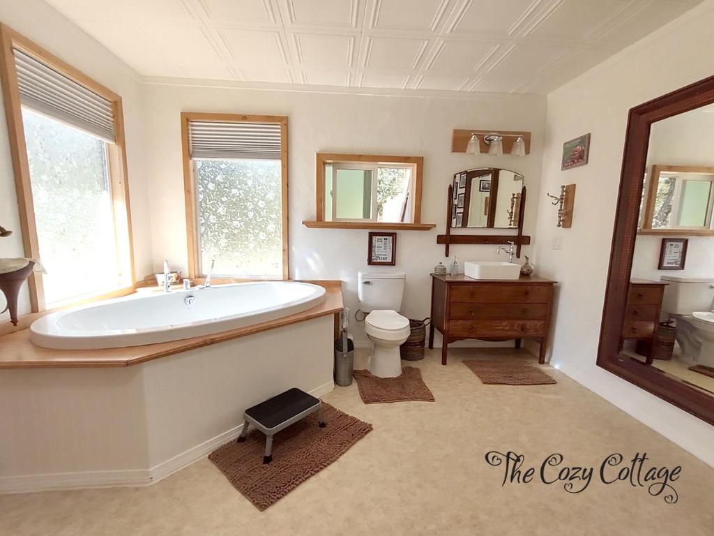 a bathroom with a tub and a toilet and a sink at Cozy Cottage in Miramonte