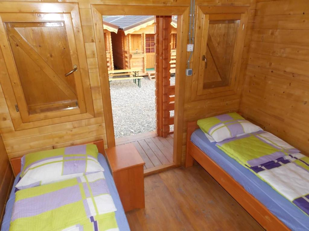 two beds in a room with wooden walls and wooden floors at Căsuțe Suzanne Băile Figa in Beclean