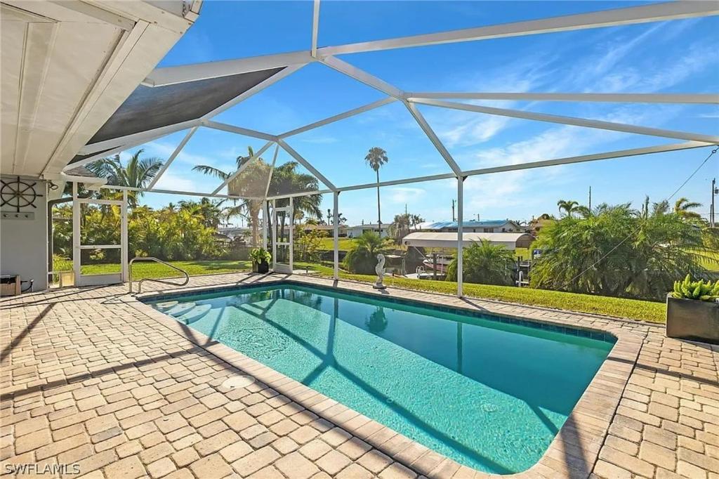 una piscina en una casa con techo de cristal en Blue Flamingo - Pool, Sunsets, Dock, Lift, Direct Gulf Access!, en Cabo Coral