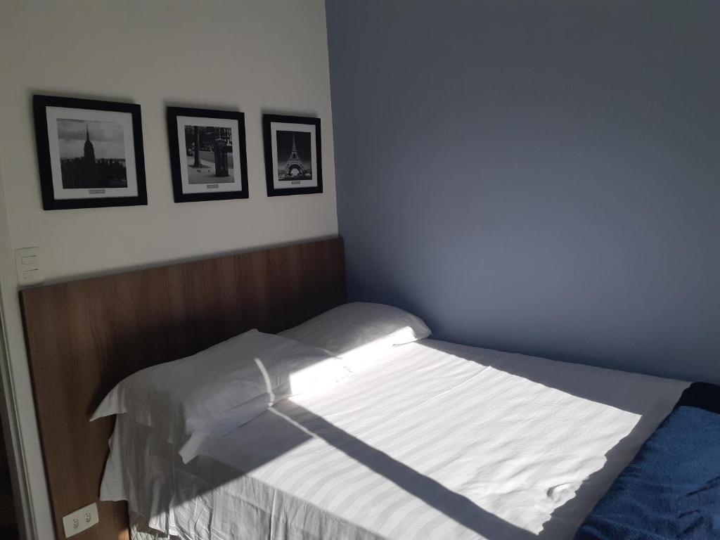 - un lit dans une chambre avec 3 photos sur le mur dans l'établissement Varanda_77 - Cely Ades, à São Paulo