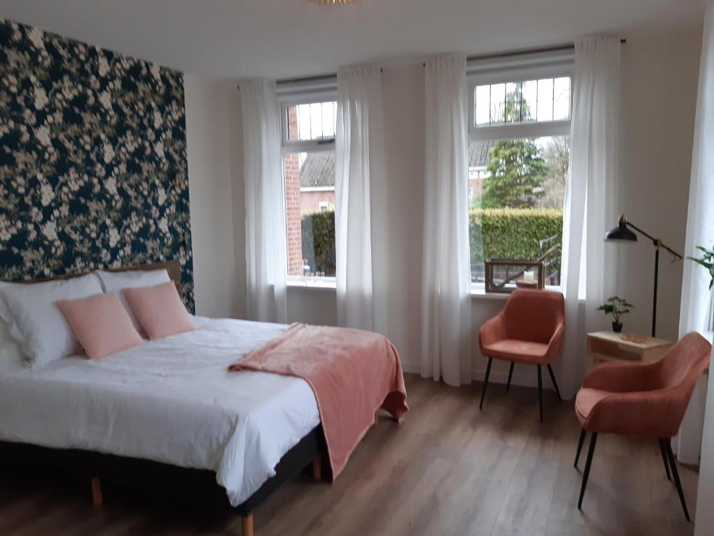 um quarto com uma cama e duas janelas em B&B het Klontje em Vriescheloo