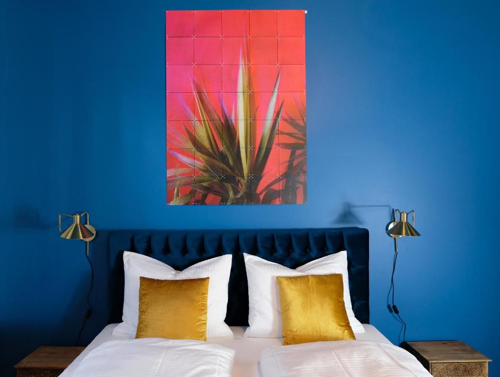 a blue bedroom with a bed with yellow pillows at Denkmalgeschützte große Boheme Altbauwohnung in Citylage in Landshut