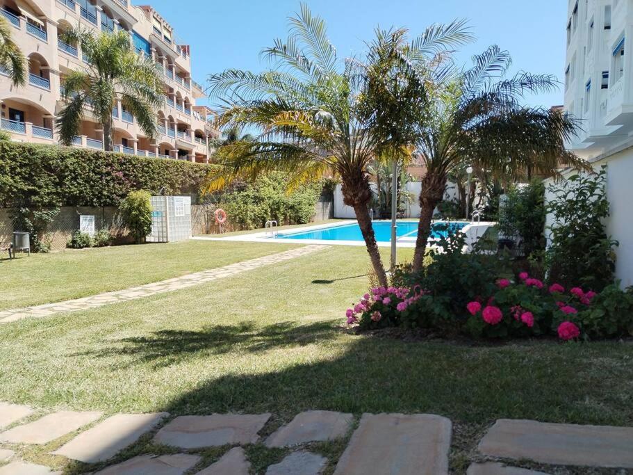 un jardín con una palmera y una piscina en Apartamento tranquilidad, playa,wifi, en Torremolinos