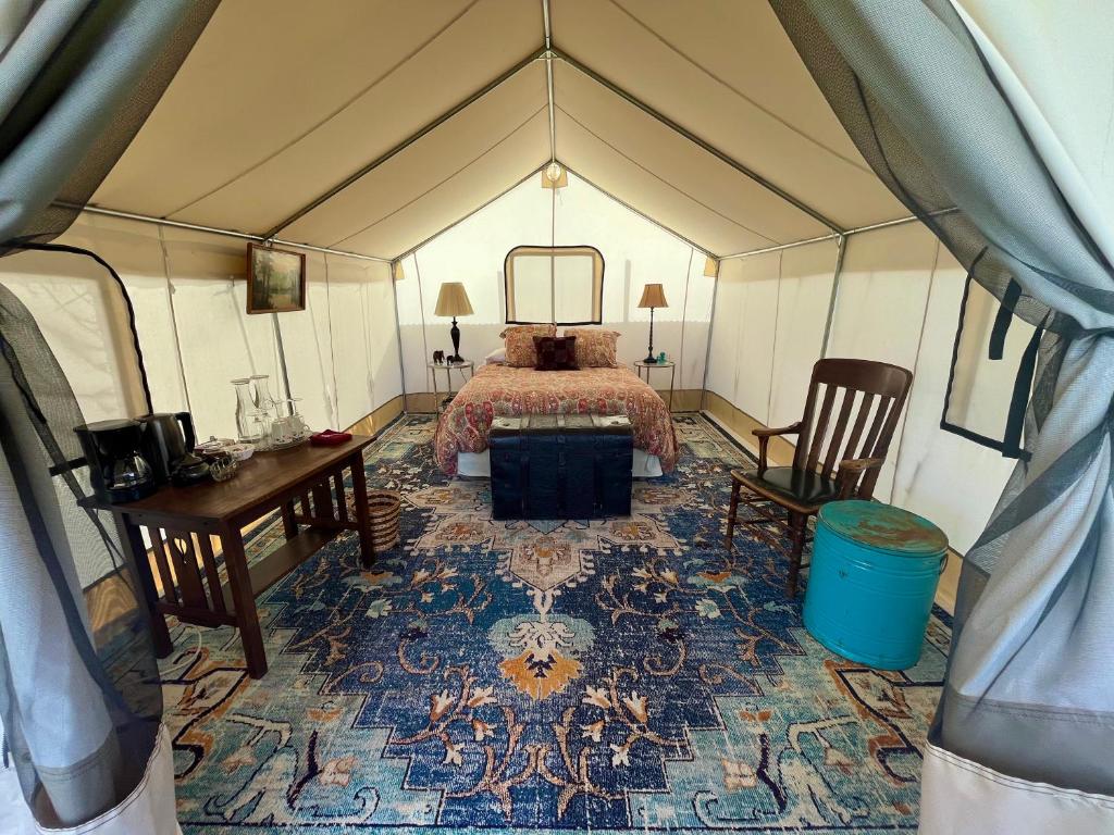 1 dormitorio en una tienda de campaña con 1 cama y 1 mesa en Zinnia Glamping Tent at Zenzen Gardens en Paonia