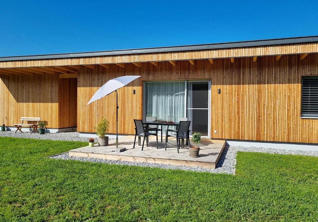 eine Terrasse mit einem Tisch und einem weißen Sonnenschirm in der Unterkunft Ferienhaus DAS GLAB in Velden am Wörthersee