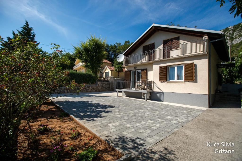 a house with a balcony and a driveway at Apartment house Silvia in Grižane