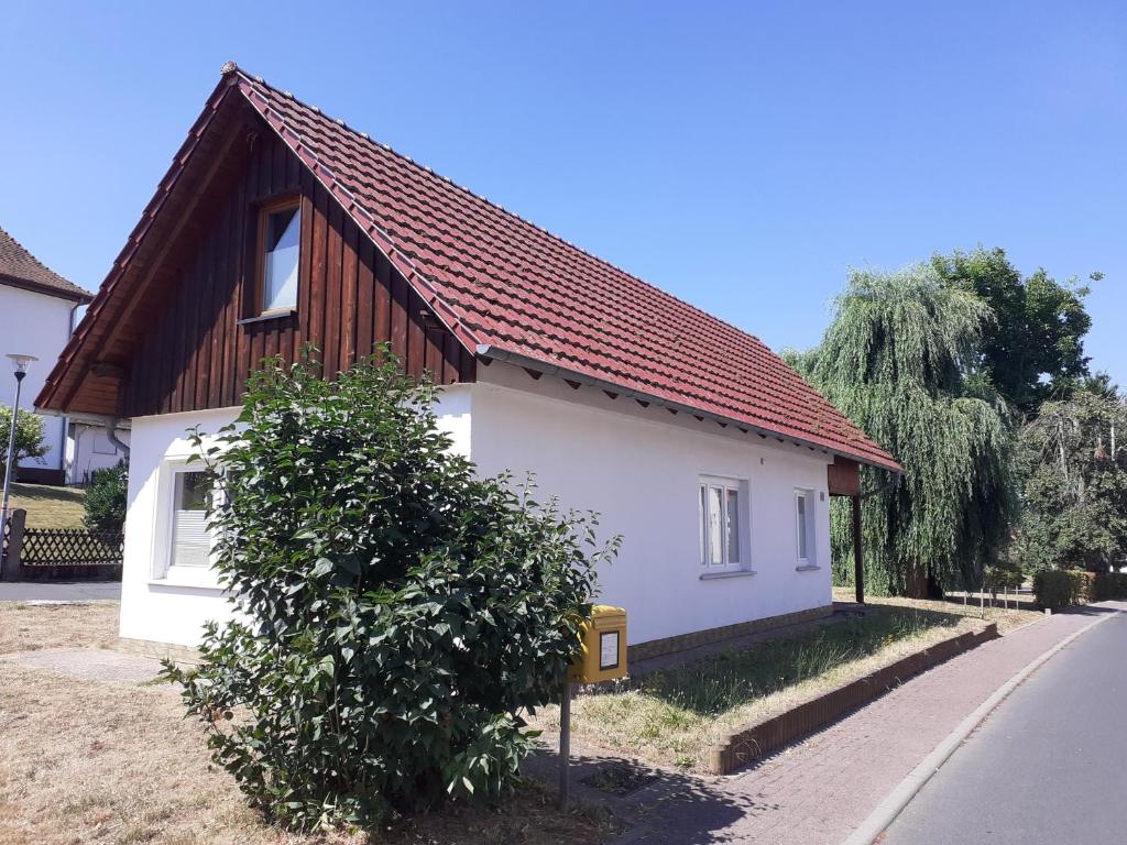 een klein wit huis met een bruin dak bij Ferienhaus Wehretal 