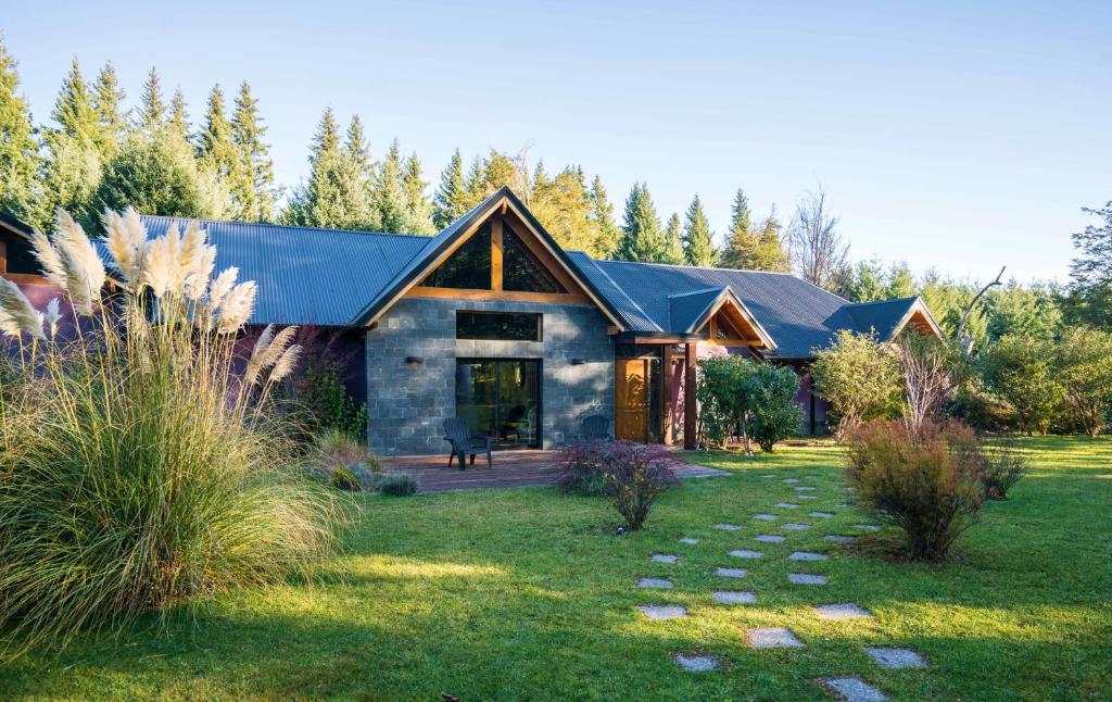 a house with a black roof and a grass yard at Arcano Casa Montaña in Villa La Angostura