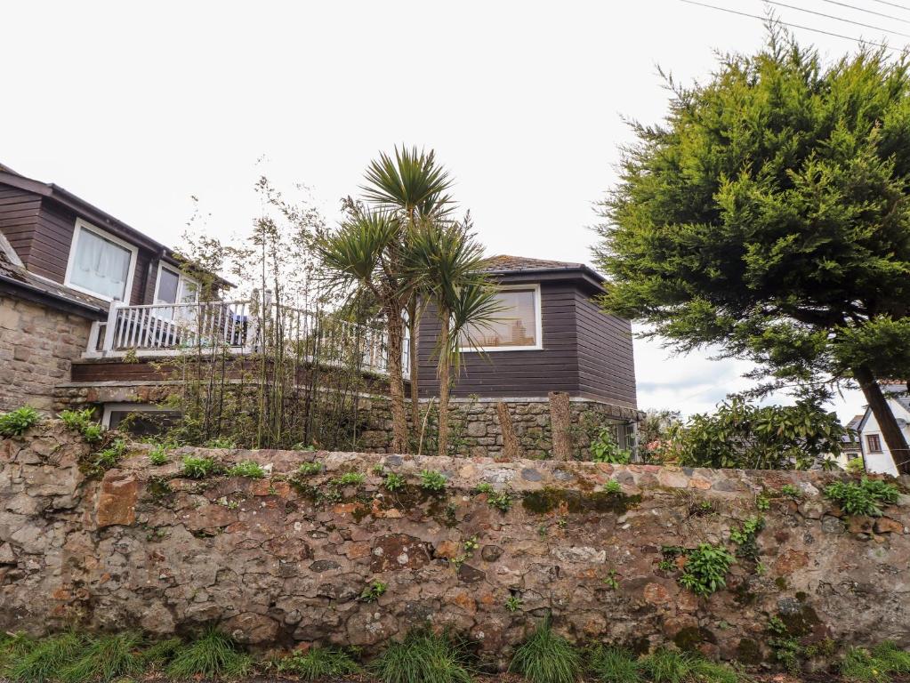 a house with palm trees behind a stone wall at The Hexagon House in Penzance