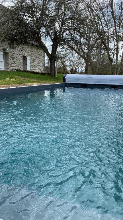 a pool of blue water in front of a house at Une pause en Corrèze in Sarroux