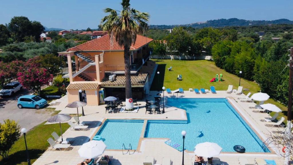 einen Blick über einen Pool mit Stühlen und Sonnenschirmen in der Unterkunft Banos Apartments and swimming pool in Roda