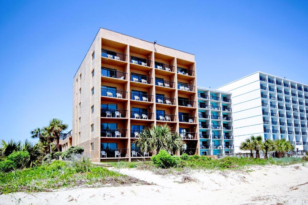 a tall building next to a beach with palm trees at South Seas Ocean Front in Myrtle Beach