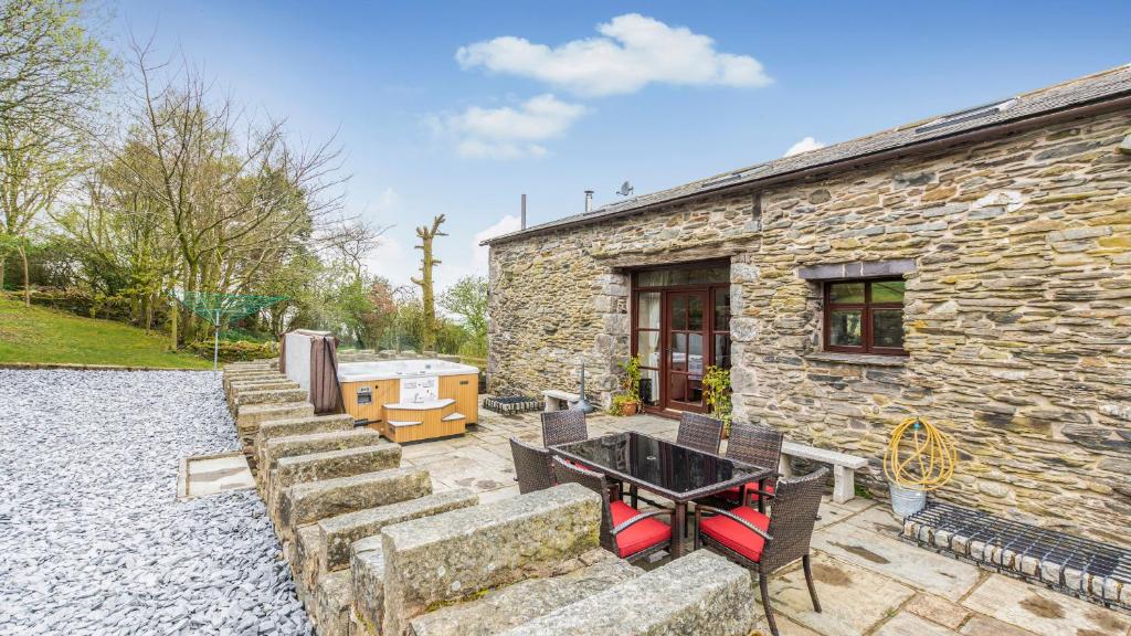 una casa de piedra con mesa y sillas al aire libre en Hill Side Barn en Ireleth