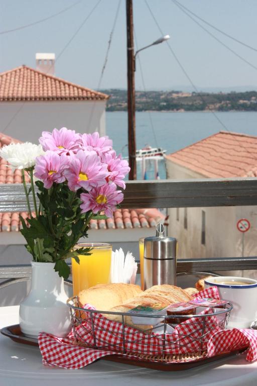 a table with a plate of food and flowers on a balcony at Kastro Hotel in Spetses
