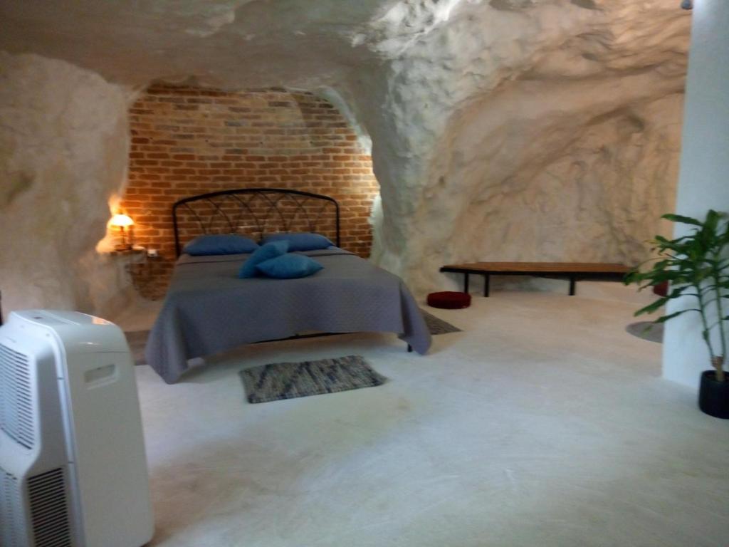 Cave house في مدينة هيراكيلون: غرفة نوم في كهف مع سرير وتلفزيون