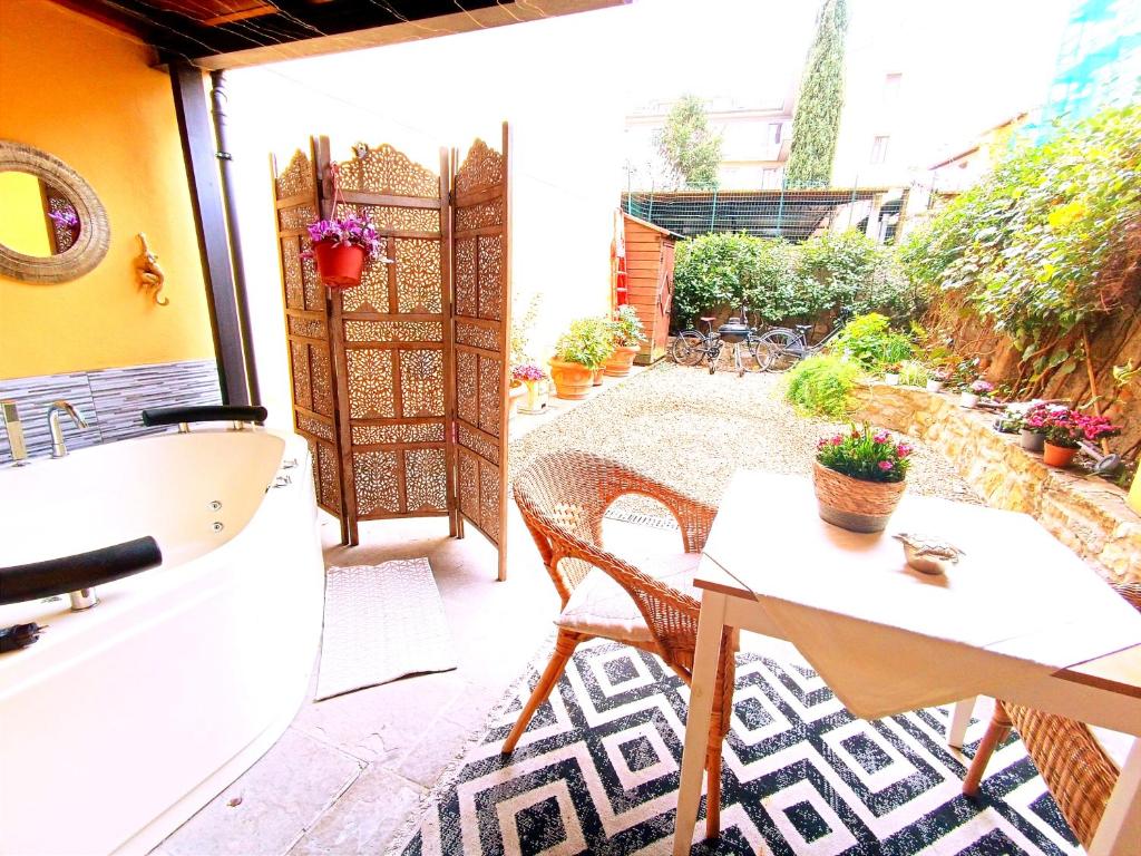 eine Terrasse mit einem Tisch, Stühlen und einem Fenster in der Unterkunft Nadia's Lovely Home - WITH PRIVATE GARDEN AND JACUZZI in Florenz