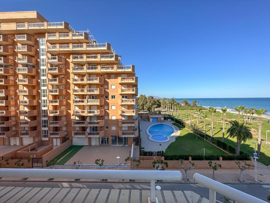 a building with a swimming pool next to the ocean at Apartamentos Be Suites Primera Linea in Oropesa del Mar